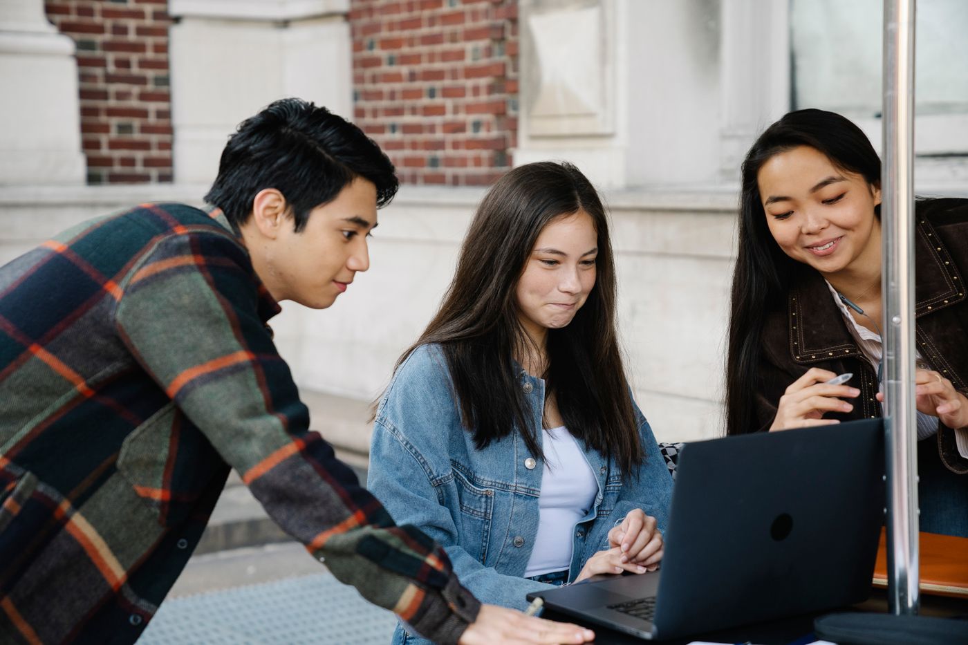 Students comparing notes around a laptop